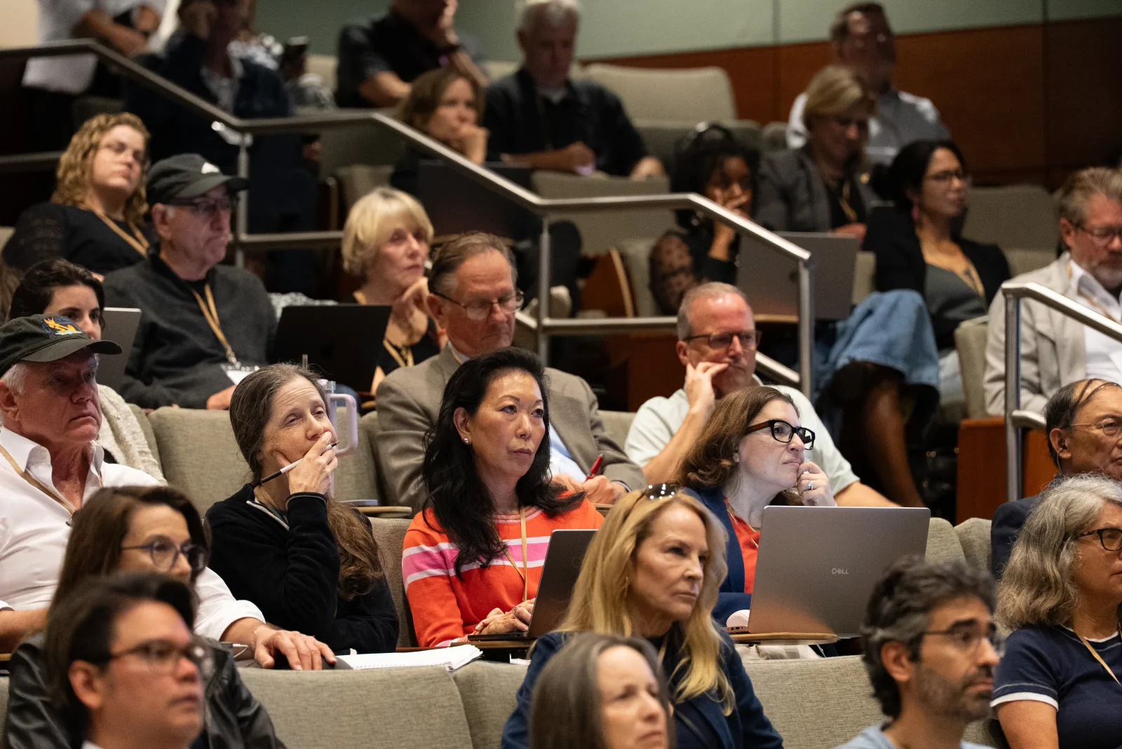 Faculty attendees watching a presentation from tiered auditorium seating.